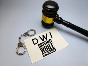 DWI – Driving While Intoxicated – displayed on a legal document alongside a judge's gavel and handcuffs, symbolizing law, crime, and legal consequences.