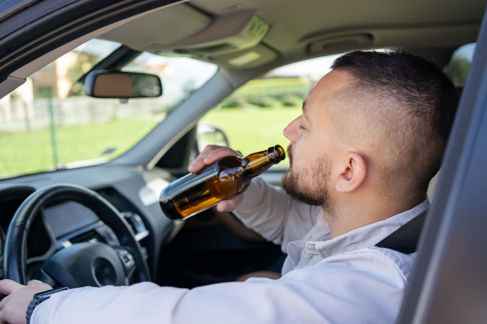 Man consuming alcohol behind the wheel—highlighting the dangers of drinking and driving. A powerful reminder: don’t drink and drive.