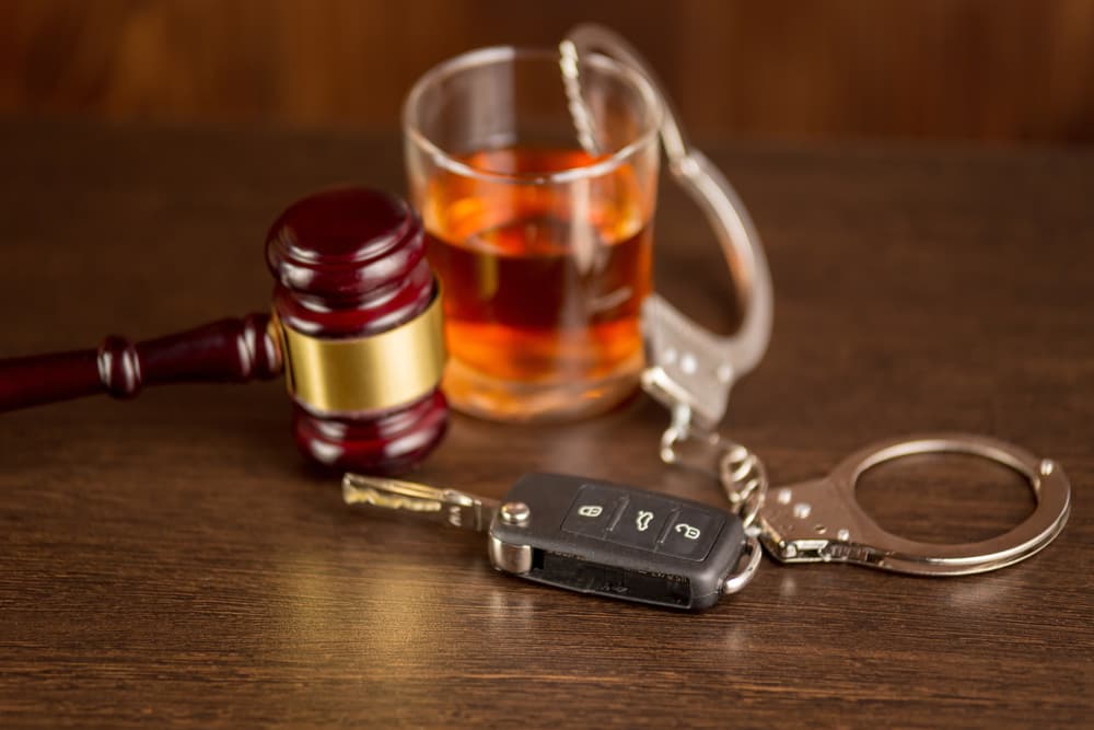 Whiskey, car keys, and handcuffs symbolize the dangers and legal consequences of drinking and driving.