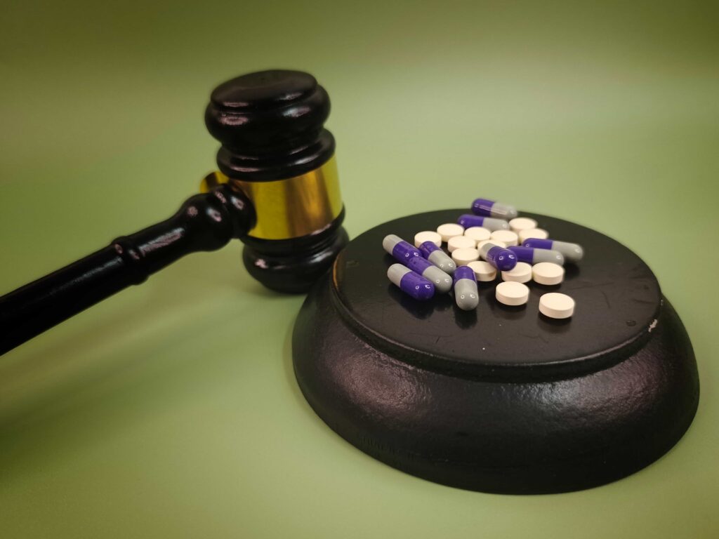 Judge’s gavel with prescription pills and capsules symbolizing drug crime and legal consequences