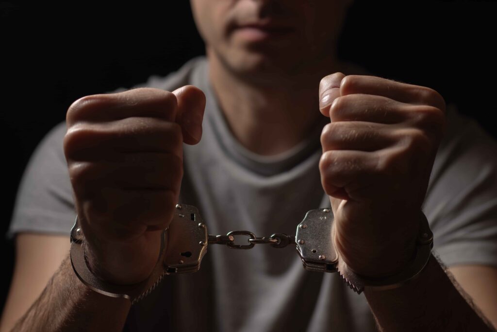 Man in handcuffs with clenched fists symbolizing arrest, criminal charges, or legal consequences.