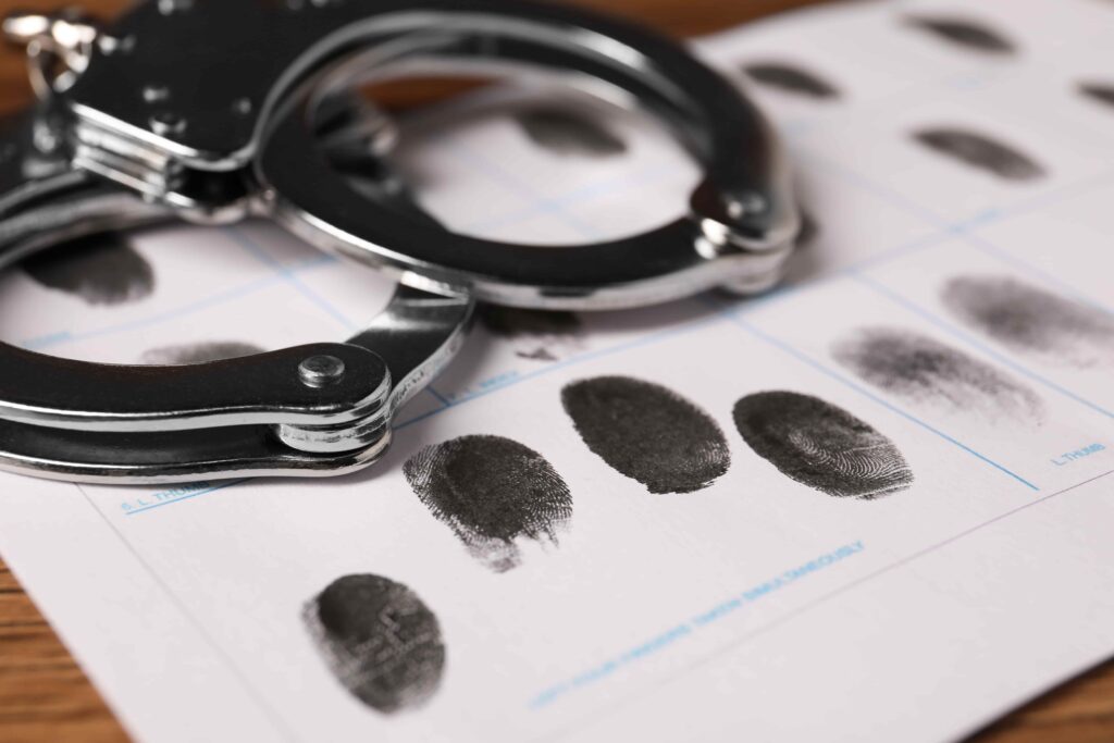 Handcuffs resting on a fingerprint card used for criminal identification and forensic analysis.